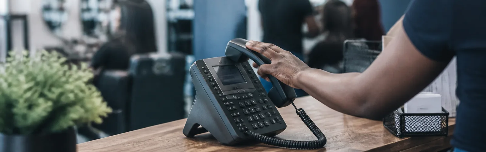 Someone reaching for a desk phone on a small shop counter